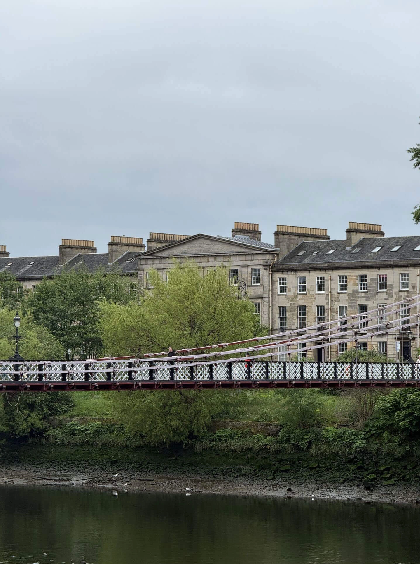 Bridge across a river beside a row of stone buildings
