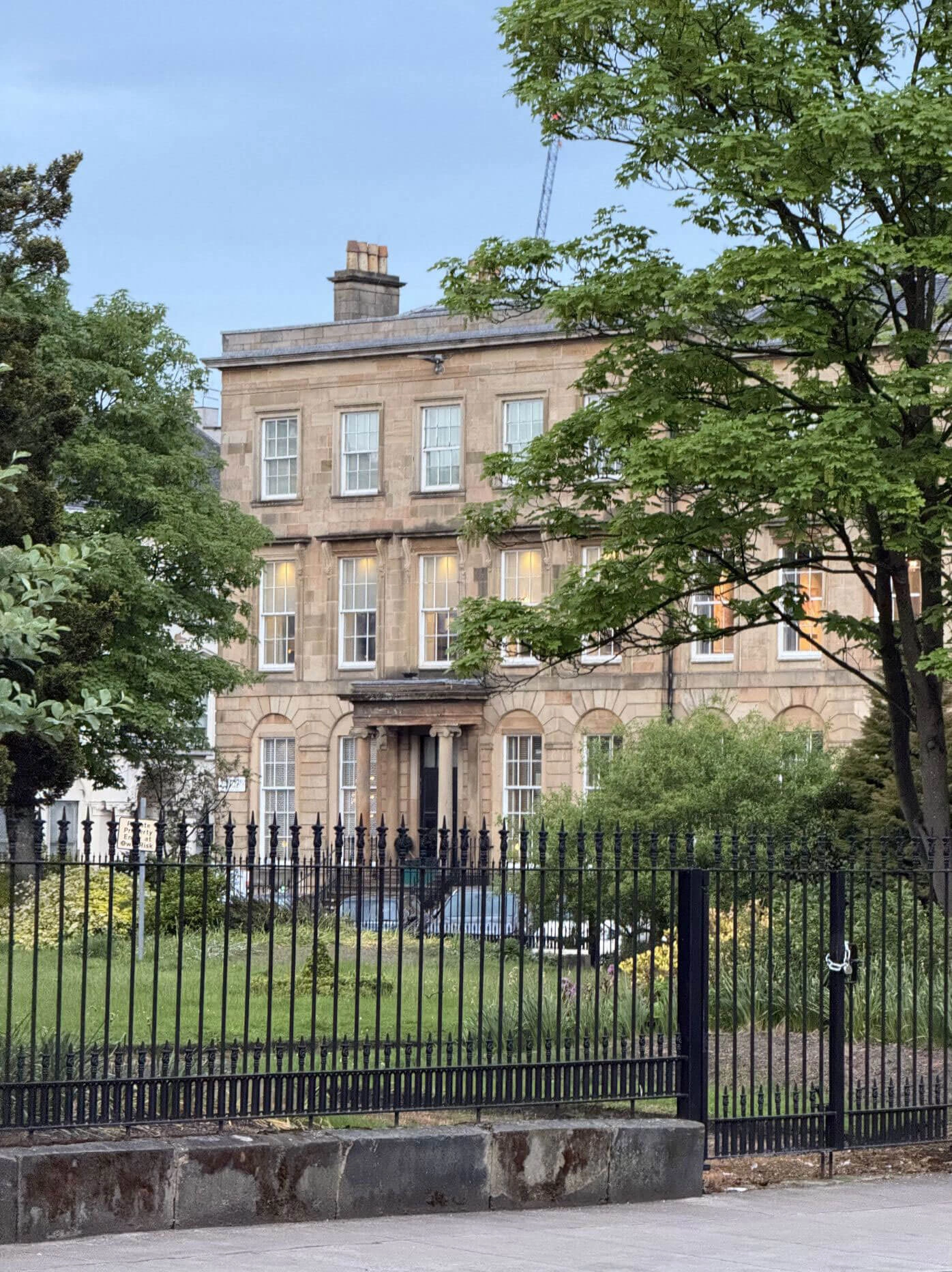 Trees and iron railings before Georgian stone facades