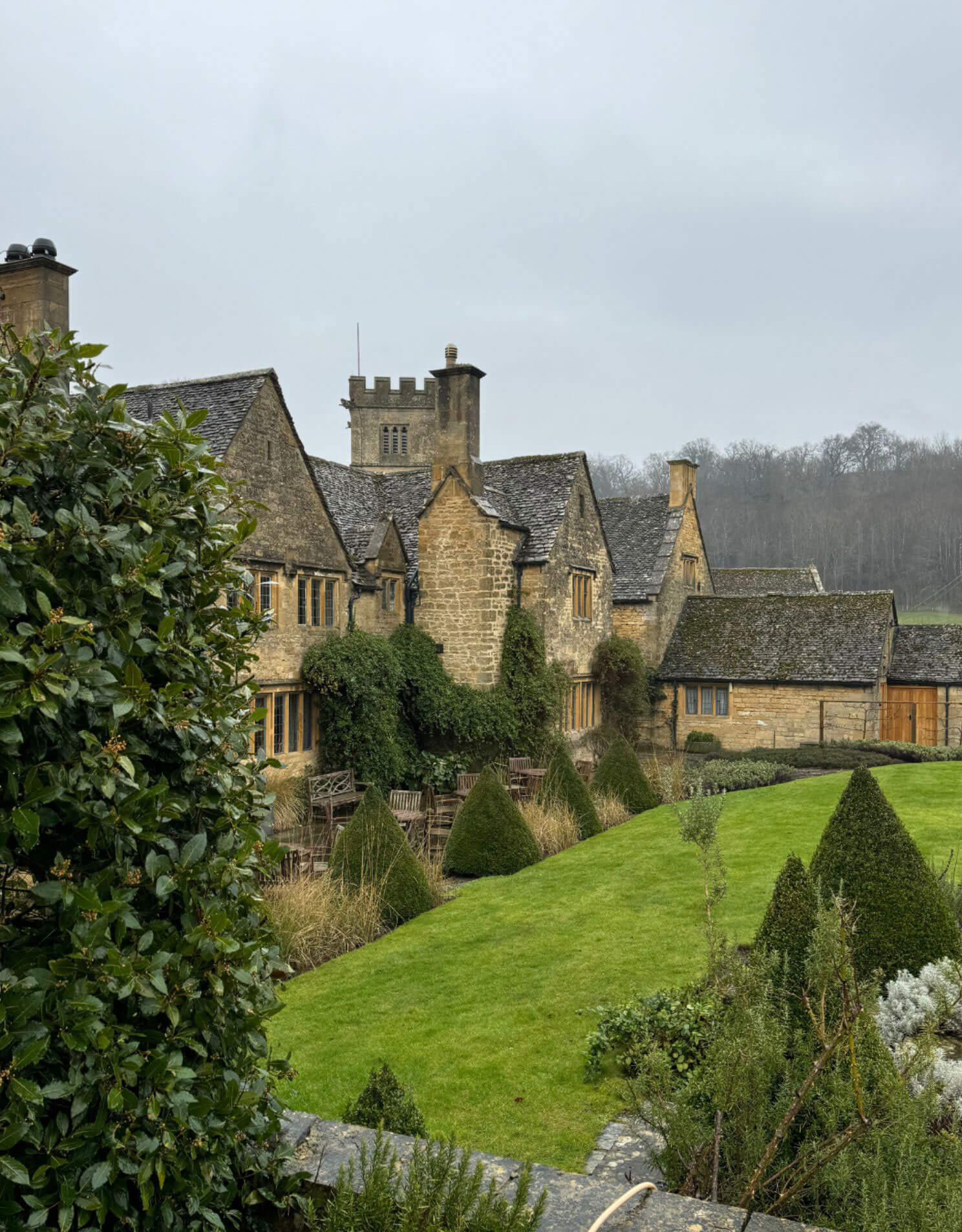 Gabled manor wings and church tower beyond a lawn