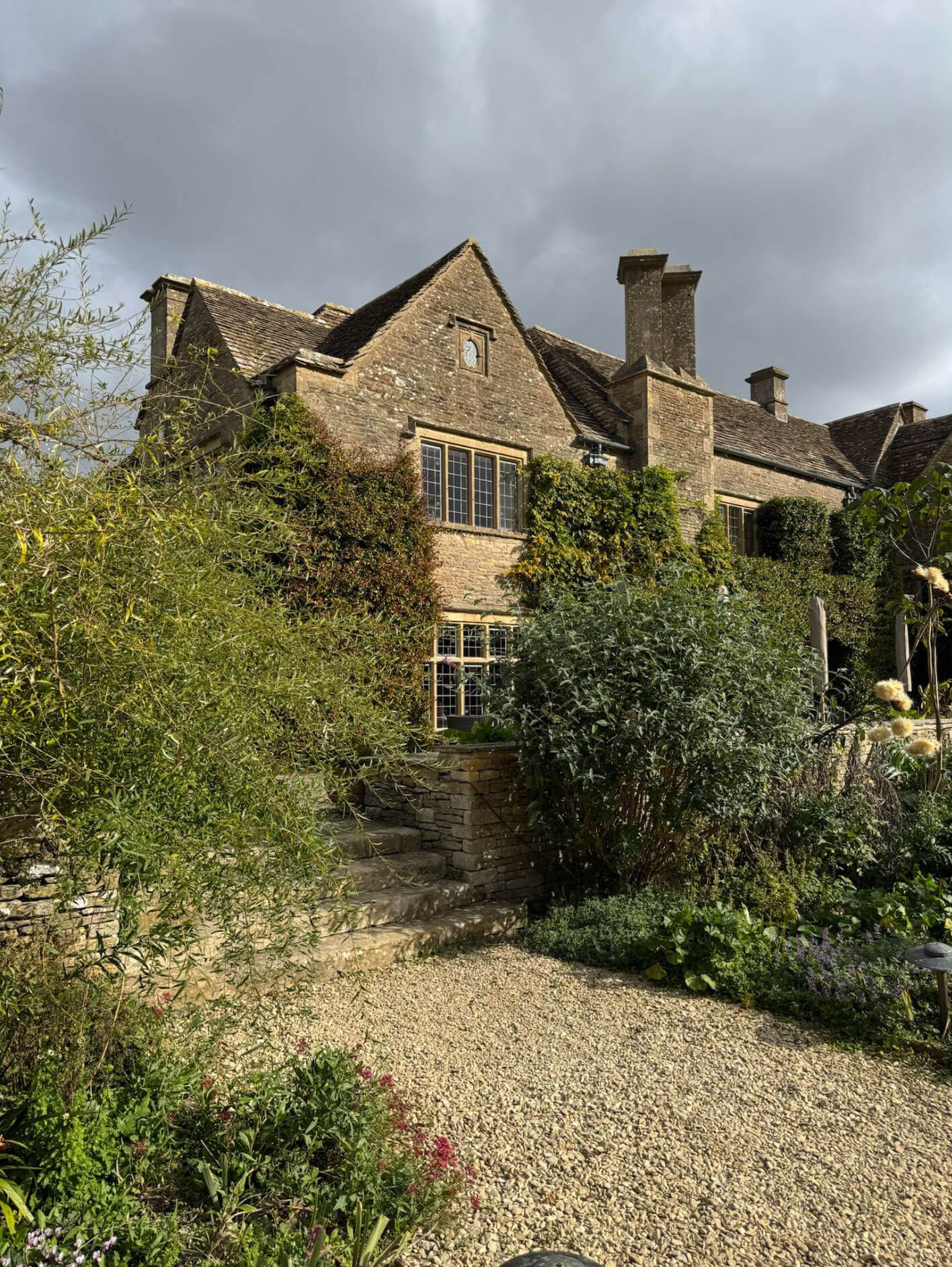 Whatley Manor behind a gravel path and garden planting