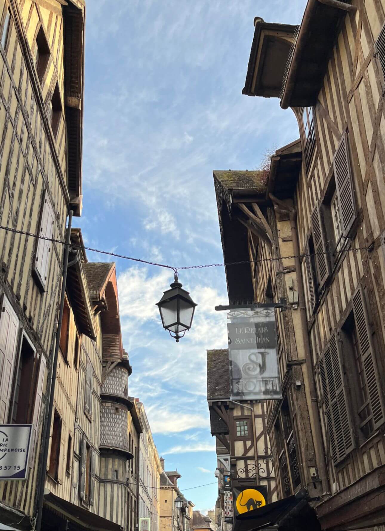 Timber-framed houses and a hanging lantern beneath blue sky
