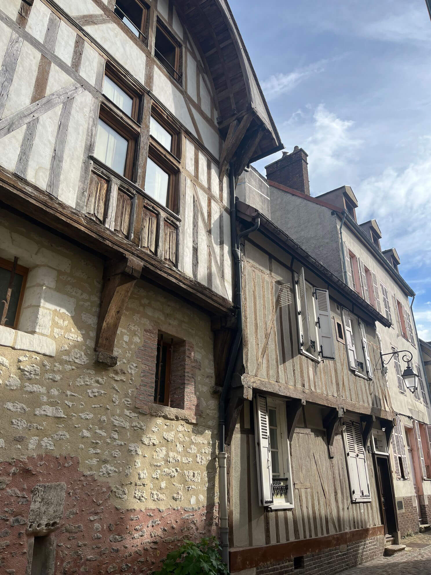 Timber upper storeys above a weathered stone street wall
