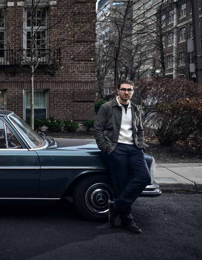 Jesse Sahlani standing beside a classic car on a tree-lined city street