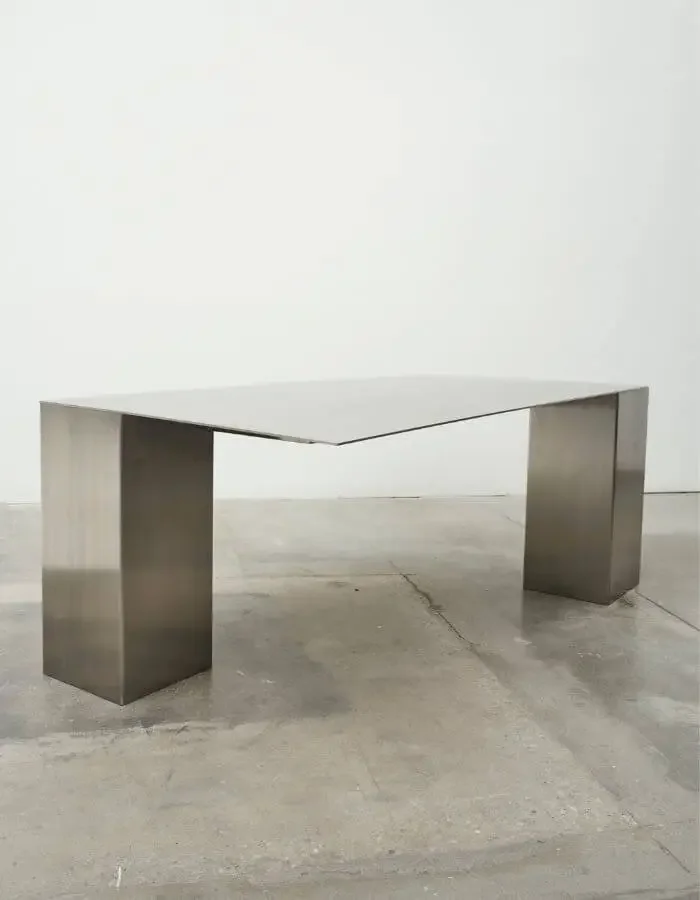 Minimalist metal sketching table with a reflective top and broad rectangular legs