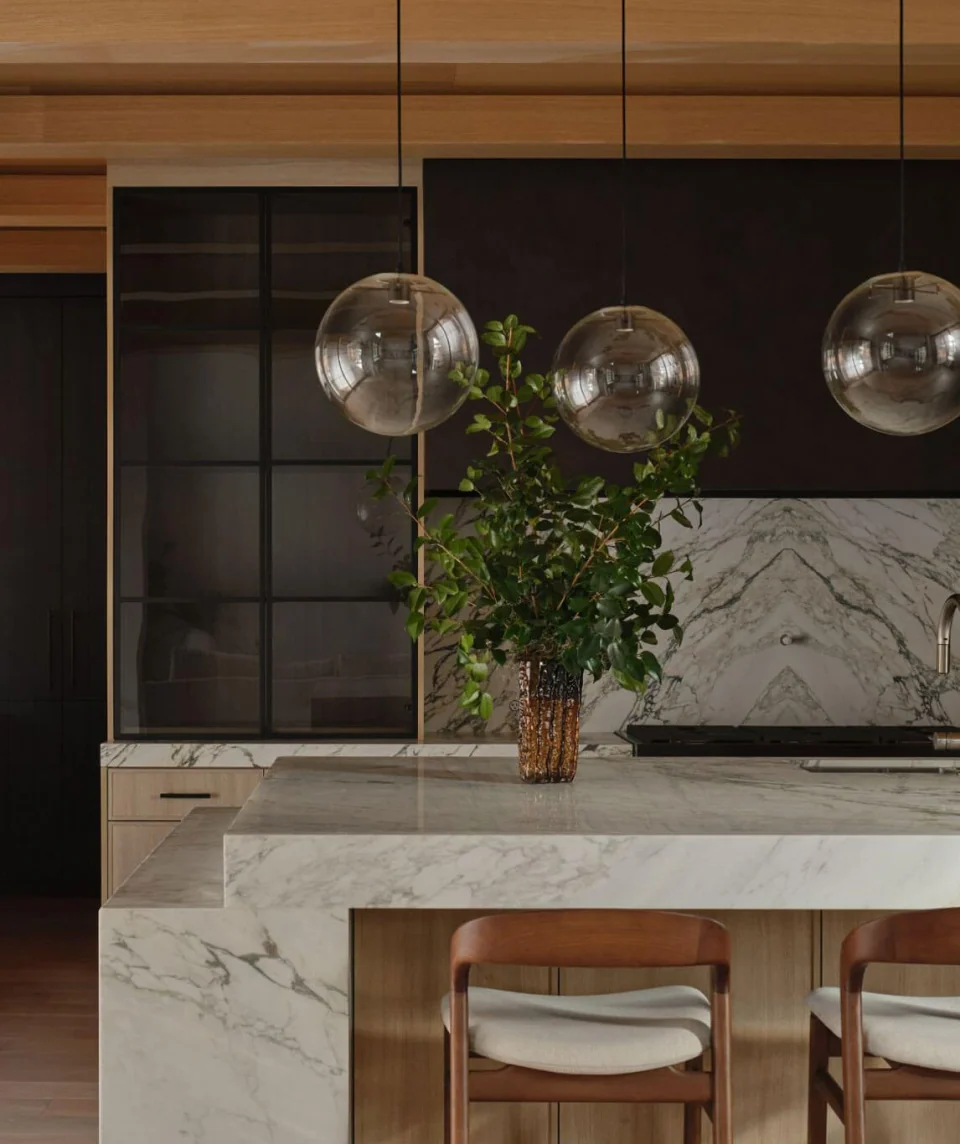 Marble kitchen island with upholstered stools and glass globe pendant lights