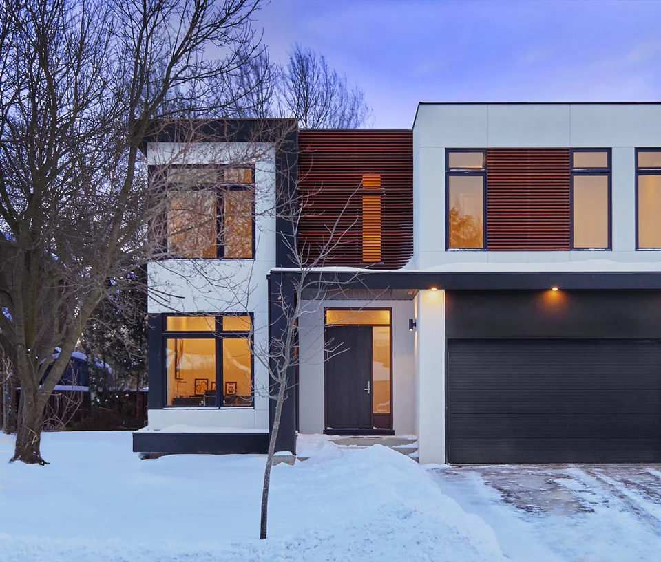 Contemporary two-storey home with a flat roof and wood accents in a snow-covered garden